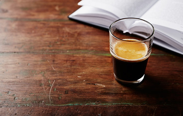 Glass of Espresso and a Book on an old Wooden Table