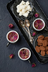 Floral tea made from rose petals and cookies on a dark gray concrete background. Tea drinking in eastern style.