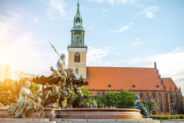 Morning view on Neptune fountain with saint Mary church in Berlin city