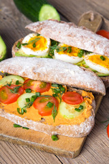 Sandwiches with avocado, eggs and tomato on a wooden background. Fresh organic vegetables, eggs and whole wheat bread. Healthy breakfast. Retro style.