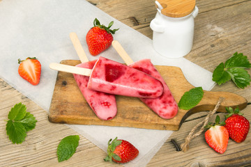 Fresh homemade strawberry ice cream on wooden background. Organic and vegan popsicles