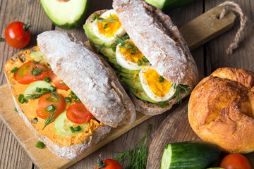 Sandwiches with avocado, eggs and tomato on a wooden background. Fresh organic vegetables, eggs and whole wheat bread. Healthy breakfast. Retro style.