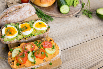Sandwiches with avocado, eggs and tomato on a wooden background. Fresh organic vegetables, eggs and whole wheat bread. Healthy breakfast. Retro style.
