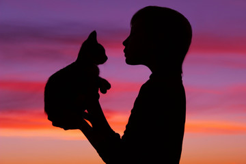 Children, pets, people and childhood concept. Cropped shot of a silhouette of a girl holding her...