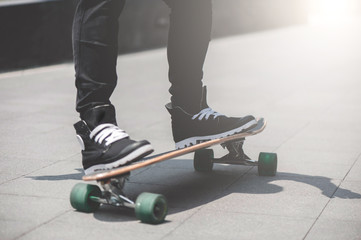 Close up of skater's legs on the longboard riding at the street in outdoors
