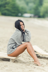 Beautiful dark-haired girl posing on the beach in a black swimsuit