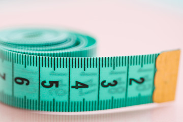 Close-up of blue measuring tape on the pink background