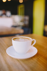 Close up view of white cup of coffee on wooden bar counter