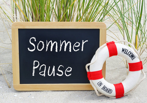 Sommerpause - Kreidetafel mit Rettungsring am Strand - Sommerurlaub, Betriebsferien, Sommerferien