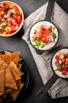 Mexican, LatinAmerican cuisine. Queso blanco recipe - cream cheese, cream, fresh stewed vegetables tomatoes, onions, peppers,  herbs. With Baked Tortilla Chips, black stone table. Top view copy space