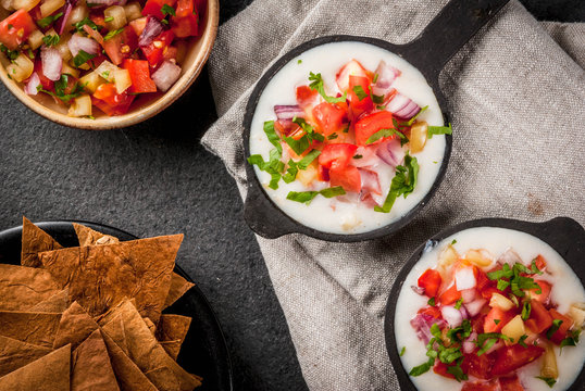Mexican, LatinAmerican cuisine. Queso blanco recipe - cream cheese, cream, fresh stewed vegetables tomatoes, onions, peppers,  herbs. With Baked Tortilla Chips, black stone table. Top view copy space