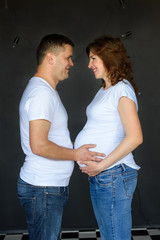 Pregnant woman with husband. Happy family expecting baby on black background
