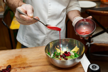 Chef is adding sauce to bowl with vegetable appetizer
