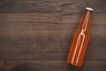 glass bottle of orange soda drink on wooden background