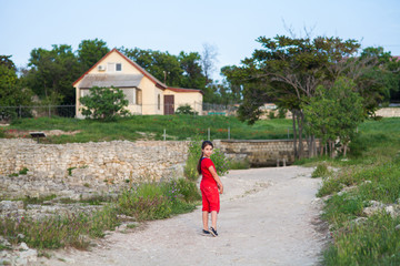 Fototapeta na wymiar girl in red shorts and t-shirt walking on a country road to the cottage