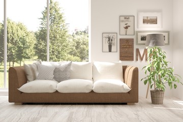 Fototapeta premium Idea of white room with sofa and summer landscape in window. Scandinavian interior design. 3D illustration