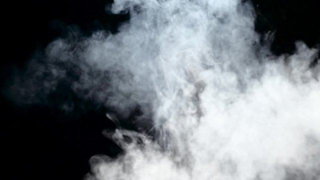 Smoke from an electronic cigarette is spreading in an empty room. Black background