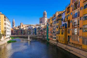 Colorful red, orange and yellow houses and bridge through river Onyar in Girona, Catalonia, Spain. Scenic ancient town. Famous tourist resort destination perfect place for holiday and vacation