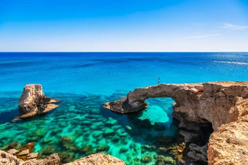 Wall murals Cyprus Woman on the beautiful natural rock arch near of Ayia Napa, Cavo Greco and Protaras on Cyprus island, Mediterranean Sea. Legendary bridge lovers. Amazing blue green sea and sunny day.