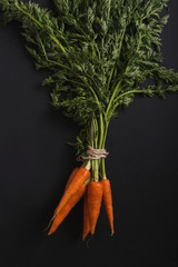 A bunch of carrots. Carrots with stems. Carrots on a black background