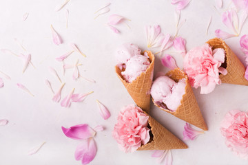 Ice cream in a waffle cone on a light background. Strawberry ice cream. Flowers in a waffle cone. Pink carnations. Flowers on a wooden  background. Copyspace. Flower photo concept.
