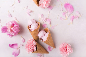 Ice cream in a waffle cone on a light background. Strawberry ice cream. Flowers in a waffle cone. Pink carnations. Flowers on a wooden  background. Copyspace. Flower photo concept.