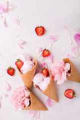 Fototapeta na wymiar Ice cream in a waffle cone on a light background. Strawberry ice cream. Flowers in a waffle cone. Pink carnations. Flowers on a wooden background. Copyspace. Flower photo concept.