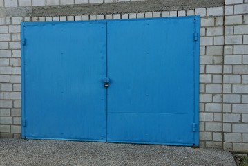 Obraz na płótnie Canvas Синие железные ворота под замком у кирпичного гаража
