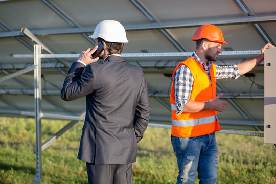 Director and engineer, solar panels construction. Head of solar station talking on phone.