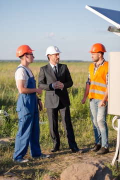 Head of solar energy station talking to engineers. Business meeting in the field.