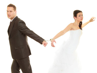 Bride and groom in handcuffs wearing wedding outfits