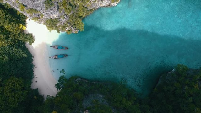 Aerial drone view of tropical turquoise water Loh Samah Bay surrounded by limestone cliffs and happy woman catching drone on the beach