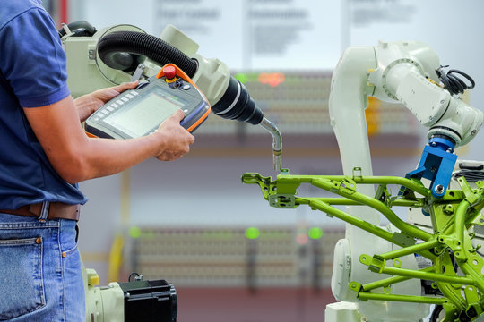 Engineer using wireless remote for control industrial robot
