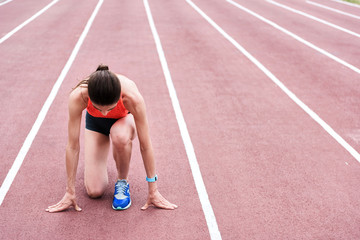 Concentrated female runner standing at starting position