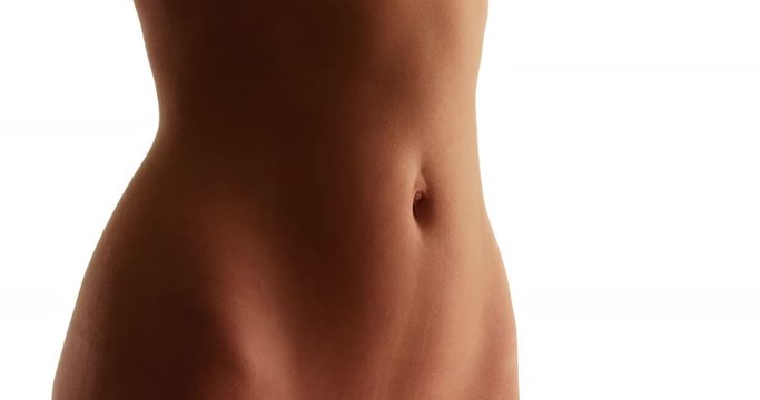 Close up of young Caucasian woman's flat stomach on white background with copyspace. Closeup of white female's fit abdomen and tan skin in studio with copy space . 4k 