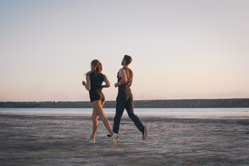 Fototapeta premium Potomstwa dobierają się bieg na plaży przy wschodu słońca tłem