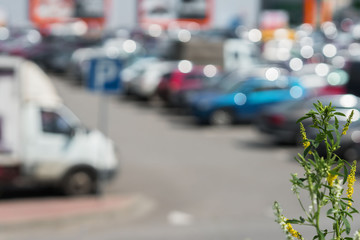 Blurred outdoor parking next to modern shopping mall, sunny summer day, season sales, for abstract background