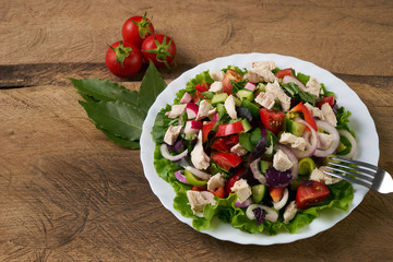 Fresh salad with fresh vegetables and chicken meat on old rustic wooden table, healthy food concept