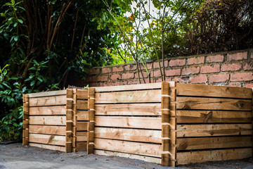 Two wooden compost bins in a back garden.