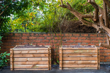 Two wooden compost bins in a back garden.