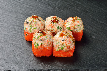 Baked sushi aji with eel, tuna, unagi sauce on a black slate surface, menu concept.