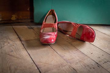 Worn red women's dress shoes on wooden floor
