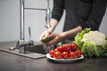 Man washing cucumbers and preparing them for cooking 