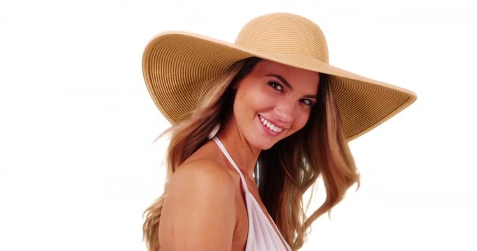 Close up of young Caucasian woman in bikini posing with floppy hat on white background. Closeup of attractive female modeling trendy sunhat in studio. 4k 