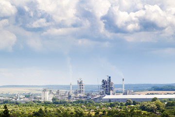 Obraz premium Industrial cement factory with pipes smoking and puffy clouds above