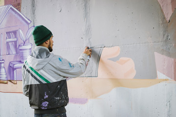 Graffiti artist with aerosol spray bottle near the wall