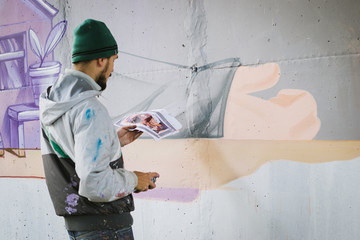 Graffiti artist painting with aerosol spray on the wall