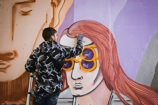 Graffiti artist painting with aerosol spray on the wall