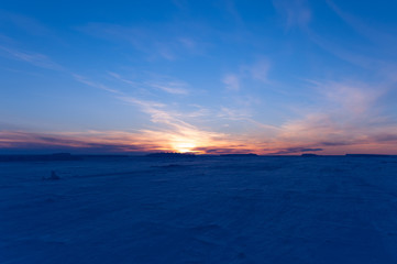 Obraz premium The frozen Weddell Sea in Antarctica at sunset with icebergs in the disdance.