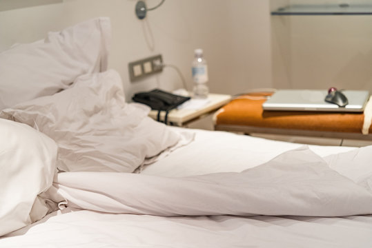 Close-up of rumpled bed with white crinkled pillows in hotel sleeping room, monochrome image